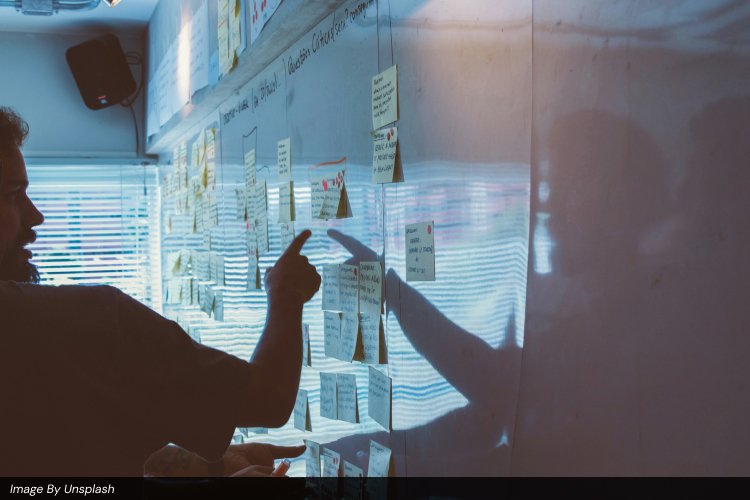 A digital marketing strategist at Ayanex pointing to a collaborative planning board with sticky notes, mapping out a business growth roadmap.
