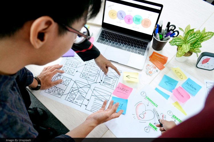 UX designer reviewing hand-drawn website wireframes and the design thinking process on a laptop
