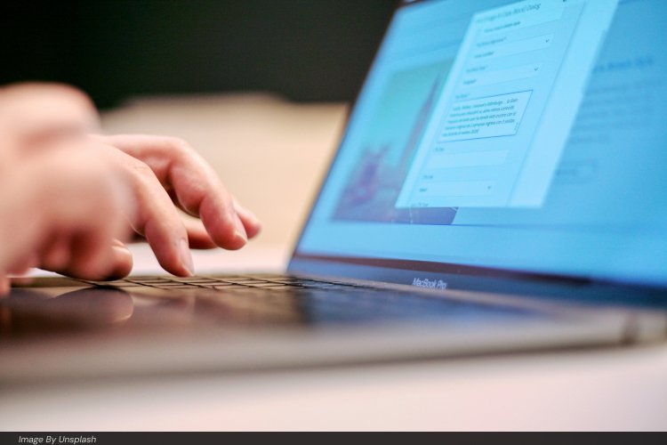 Author typing on a laptop while filling out an online book publishing form